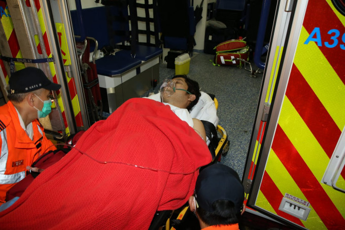 其中一名伤者由担架抬上救护车。