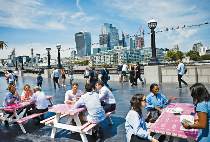 英國泰晤士河畔有上班族在休憩。對岸為倫敦金融城。