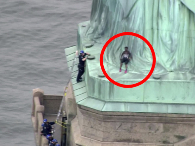 美国国庆日一名黑人女子爬上纽约自由女神像，坐在神像裙脚抗议，不满政府移民政策。AP