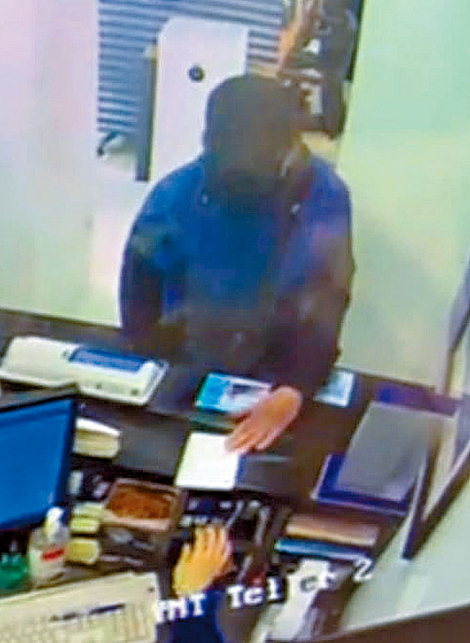 劫匪将写有「打劫」的纸条交给银行女职员后，用枪指吓。