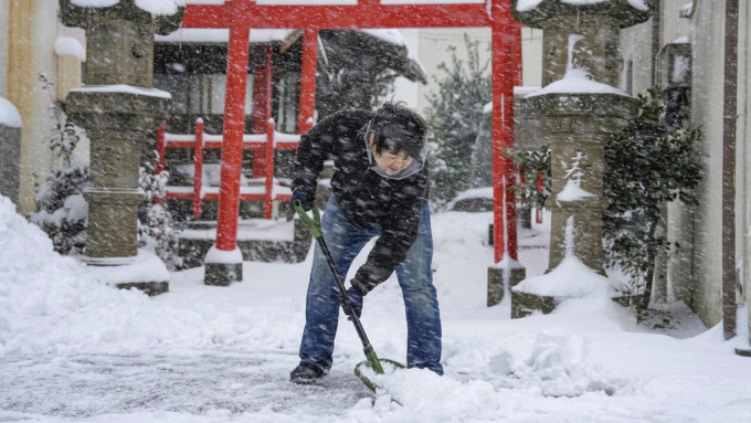 日本鸟取县鸟取市市民在神社前忙于铲雪。美联社