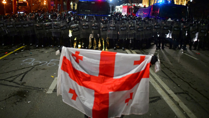 反對「外國代理人法案的」示威者，身披格魯吉亞國旗與警員對峙。 路透社
