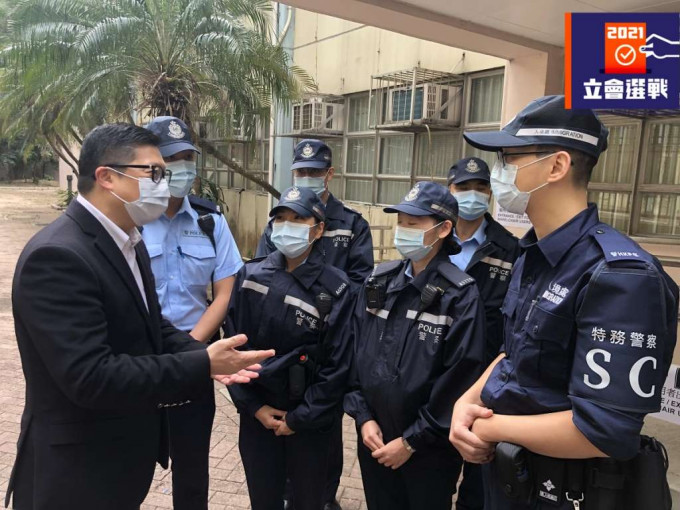 邓炳强（左一）于黄大仙的票站与驻守的特务警察交谈，为他们加油打气。政府新闻处图片