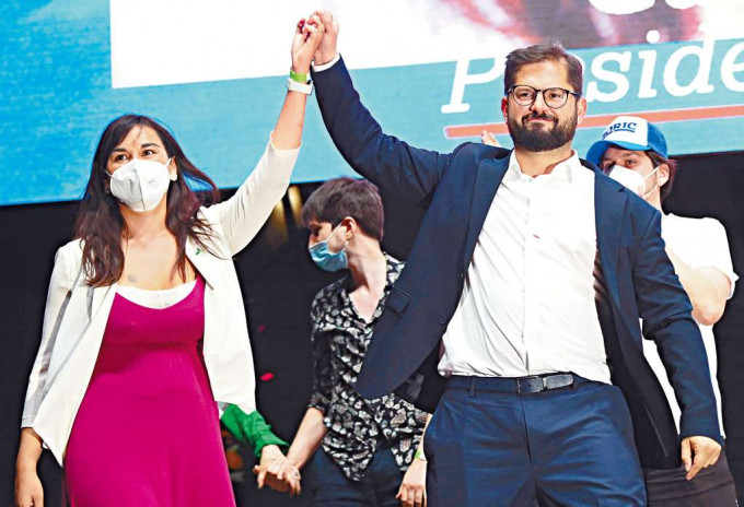 ■胜出智利总统大选的博里奇（右）与竞选经理西切斯，周日向支持者挥手致意。 
