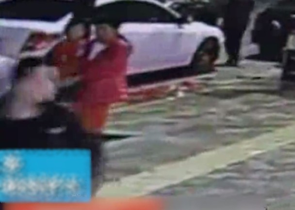 一名身穿粉红色外套的女子，在街上徘徊，当她发现女童在超市附近独自玩耍，便上前将女童抱起。(网上图片)