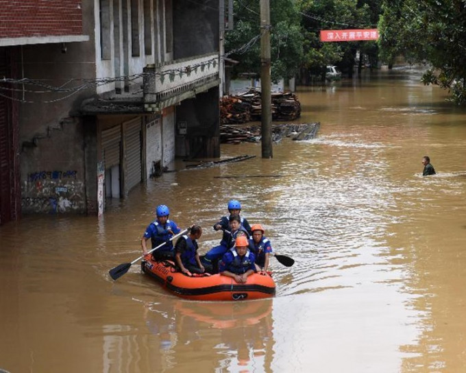 救援人員在嚴重水浸的街道協助疏散市民。新華社