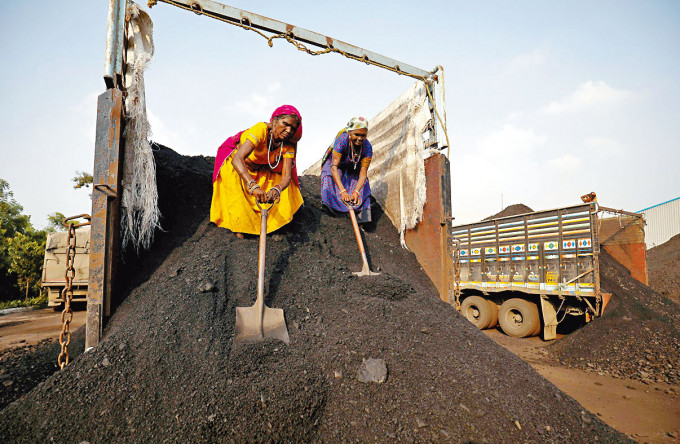 印度艾哈邁達巴德市郊一個煤場的工人從貨車卸下煤炭。