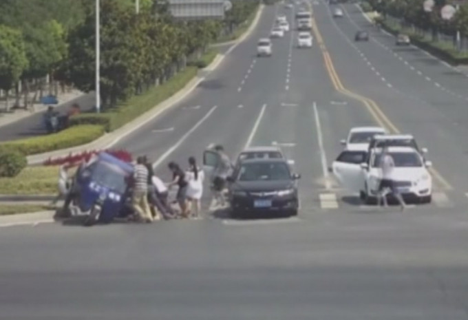 多名过司机及路人合力托起三轮车。