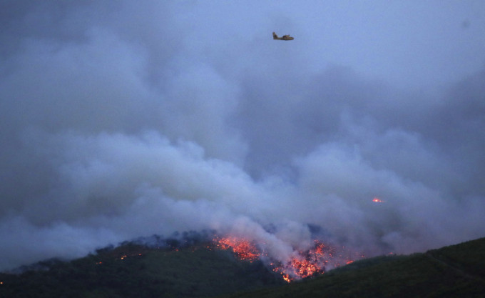 當局派出多架定翼機及直升機灌救山火。AP