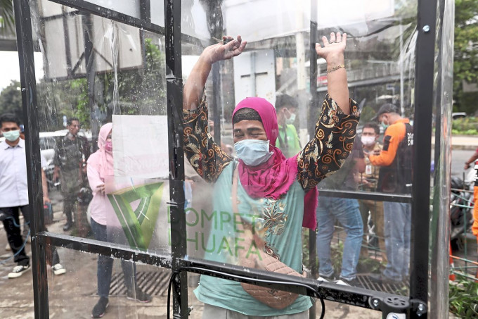 印尼一名婦女接受消毒液噴灑。AP資料圖片圖片