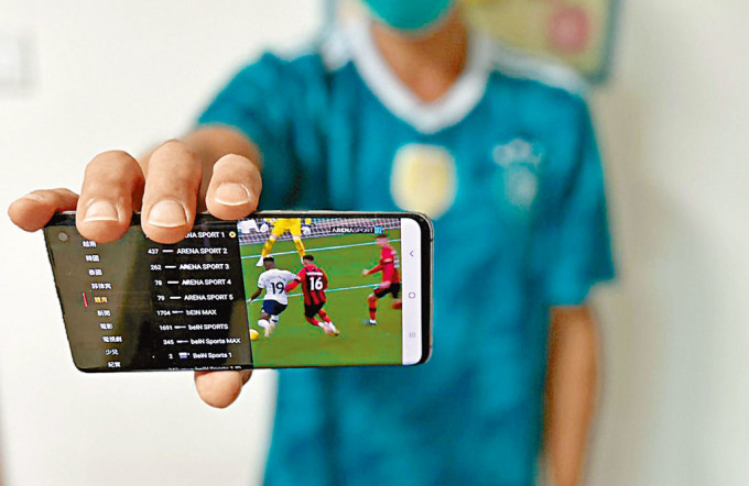 有購買了電視APP的青年展示手機畫面，當中有不少可觀看足球賽事和世界盃的外國電視頻道。