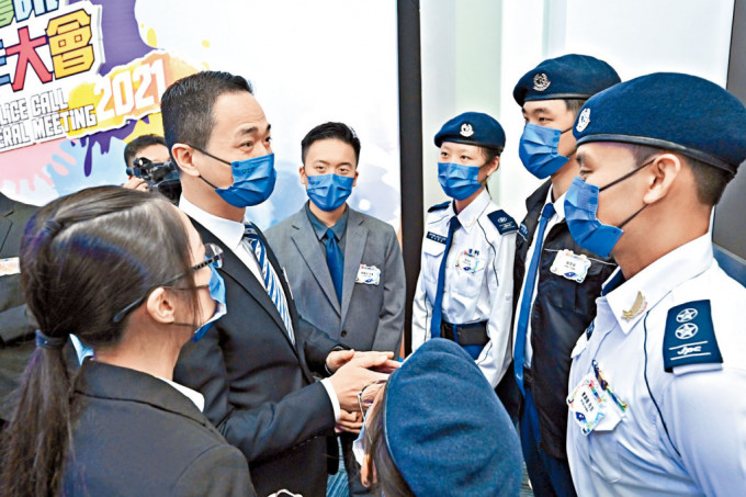 警務處助理處長（公共關係）陳東（左二）與穿着少年警訊新制服的深資領袖曹灝聰（右）交談。