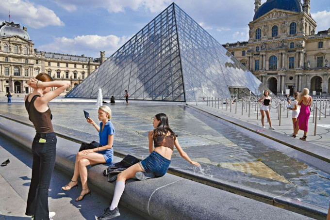 遊客在巴黎羅浮宮的庭院休息。