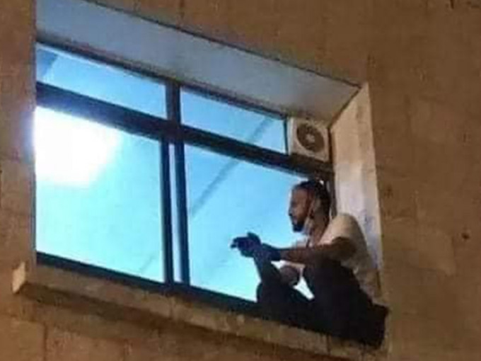相片中男子每晚爬上医院的窗户，坐在窗外陪伴染疫母亲。(网图)