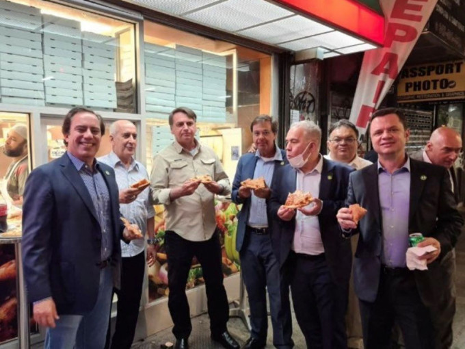 巴西总统博索纳罗（左起第三）与其他访团官员一起在路边吃披萨、喝可乐。网图