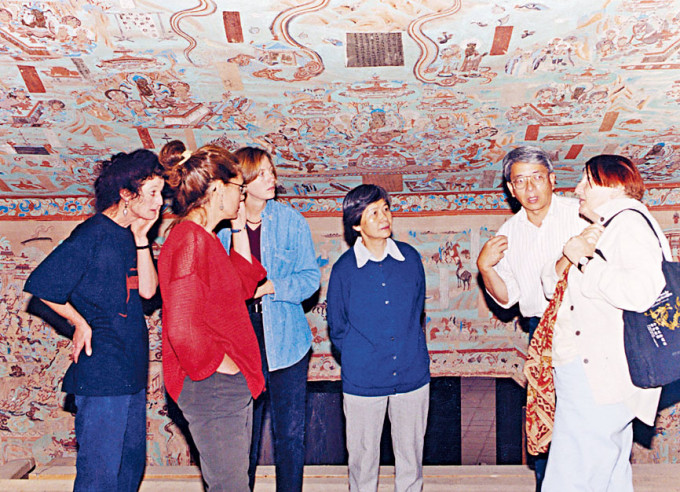 一九八八年，樊锦诗院长（中）与专家团队考察莫高窟，探讨数码化方案。