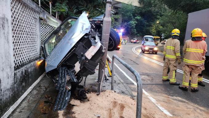 私家車失控越線並翻側，困在石牆與燈柱之間，司機一度被困車內。黎志偉攝