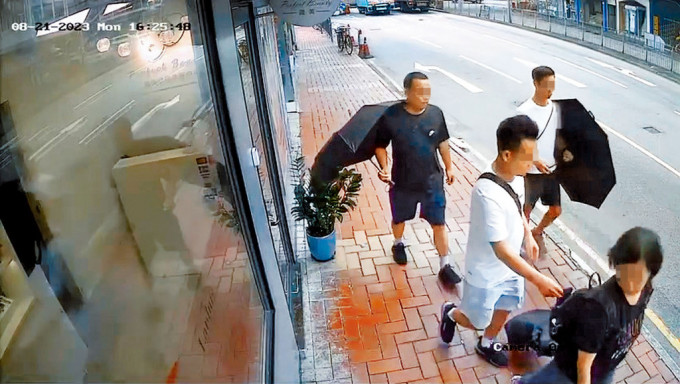 扒竊黨2人以打傘方式掩護1名同黨偷竊途人背囊內的財物。