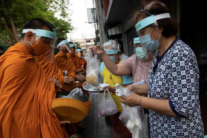 曼谷有僧侣因应疫情，外出时戴上防护装备。AP
