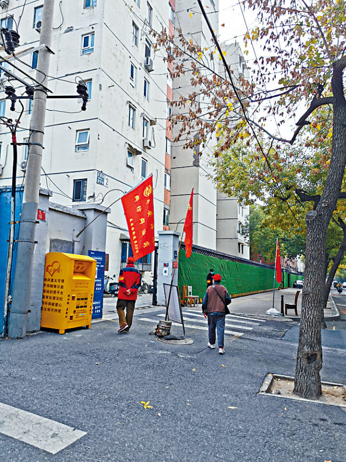 二十大气氛浓厚，北京随处可见红旗飘扬，红袖章志愿者上岗。