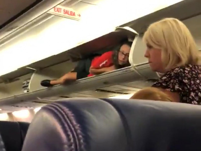 西南航空乘客登机时，发现座位上方行李架内有一位空姐。（网图）