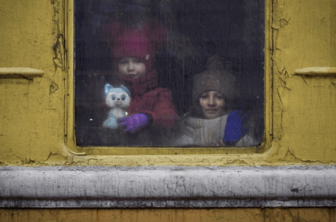 2022年3月3日，准备逃往国外的乌克兰儿童，透过暂停在利沃夫车站月台的火车上向外张望。（美联社）