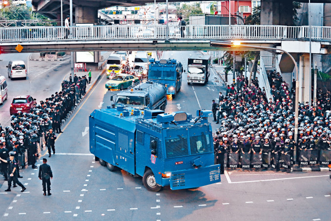 警方昨日出動的水炮車駛過曼谷街頭，道路兩旁有大批防暴警察。