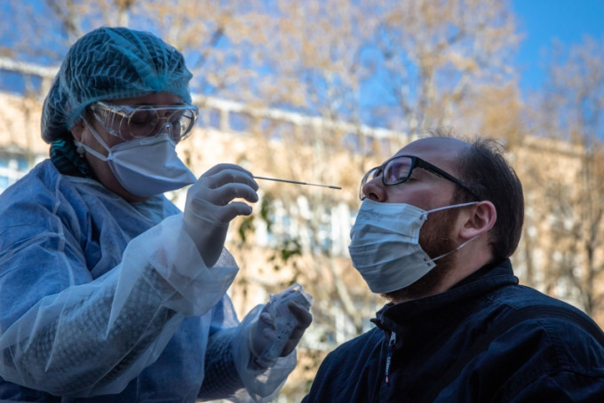 法国新冠肺炎死亡病例数在大幅攀升。在法国巴黎17区，工作人员为一名接受新冠病毒检测的医护人员取样。（新华社图片）