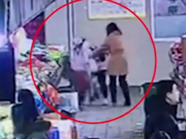 陌生妇人突然抱起女童，将其头部撞向菜摊。 网上图片