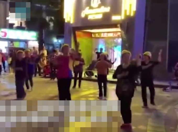 一群大妈为继续在广场上跳舞，竟不惜戴上安全帽。网图