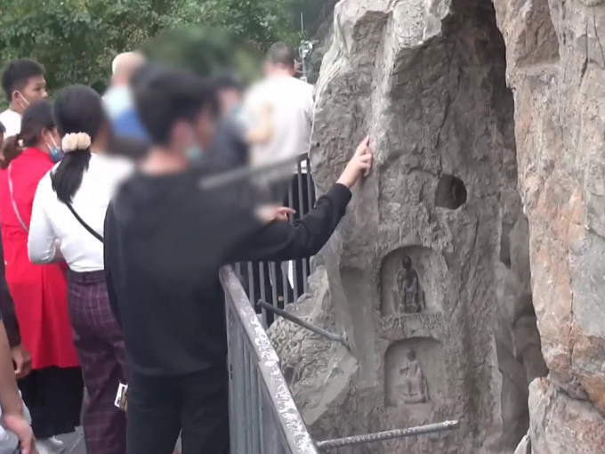 河南洛阳龙门石窟佛像被游客摸出「包浆」，引发网民热议。（网图）