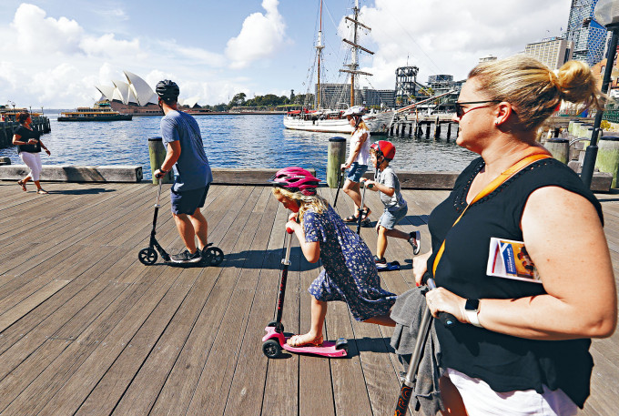 一個家庭周二在海濱走廊玩踏板車，遠眺雪梨歌劇院。