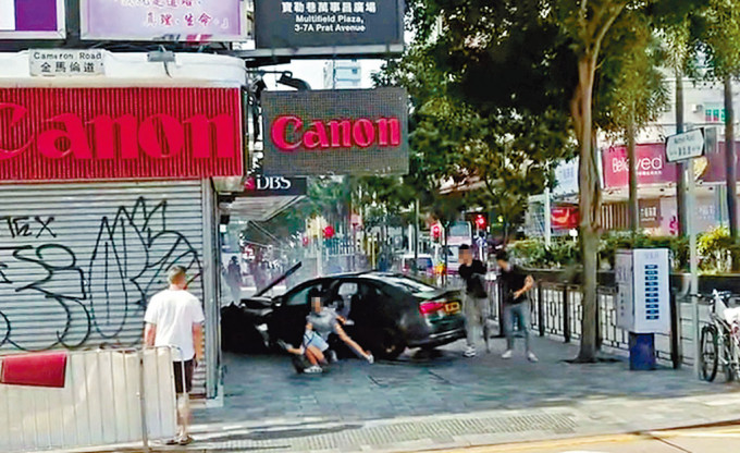 私家車撞向地鋪後，其中一名女乘客逃出車廂時失平衡仆倒地上。
