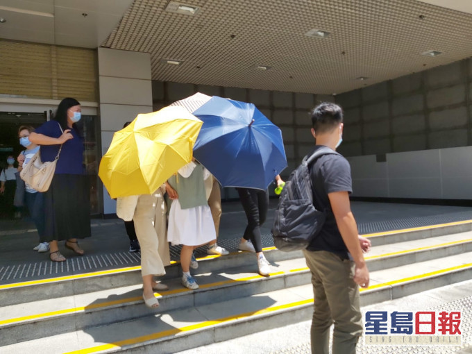 被告劉曉敏在傘陣下離開(綠白色衫)。羅綽堯攝