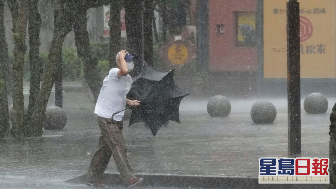 靜岡縣一名男子在大風大雨中前行。AP