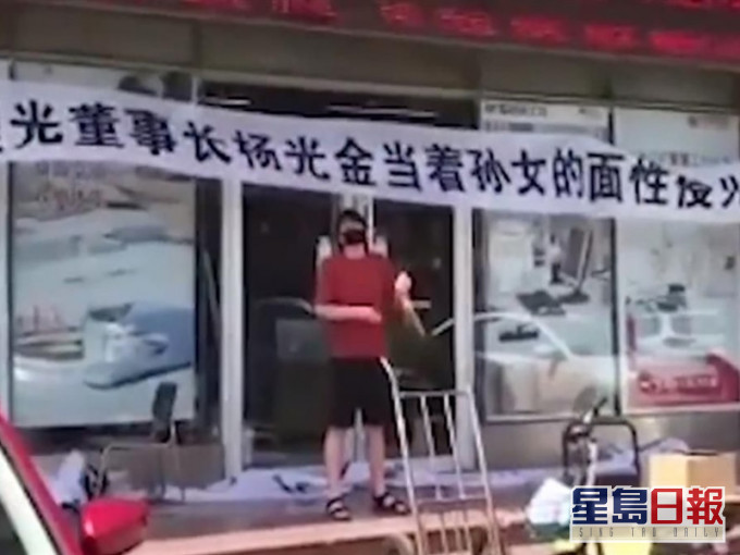 男子拉起橫額敲鑼怒喊父親喪盡天良。網圖