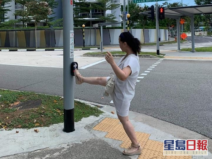 新加坡有自私大妈以脚代手「踩」红绿灯掣,引来网民炮轰。(网图)