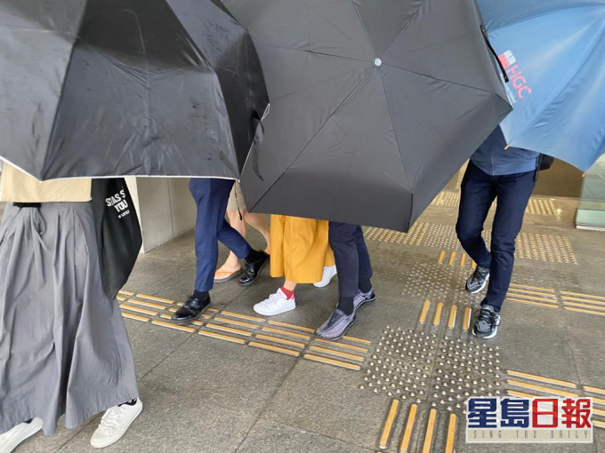 被告(左二)在伞阵掩护下离开法院。张旭珊摄