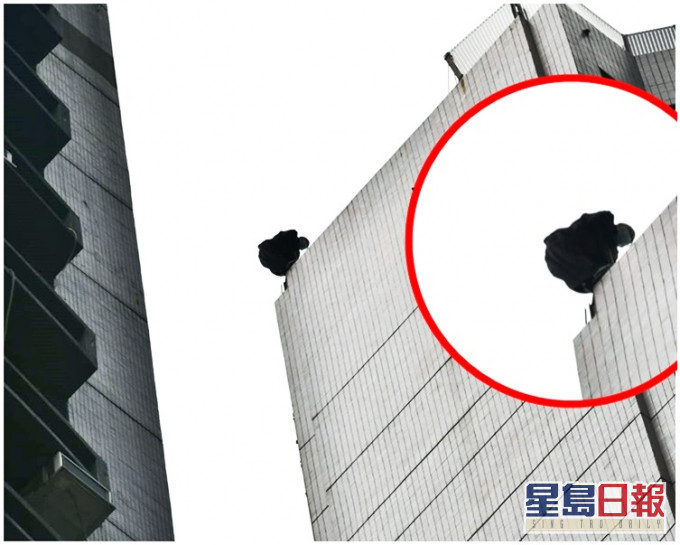 保安員在天台背向街外蹲於石壆旁,雙臂靠在鐵欄上,險象環生。