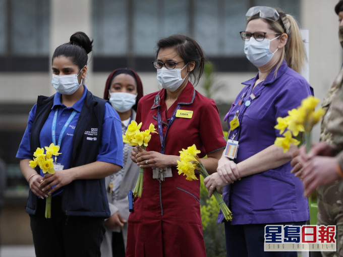 有NHS医护人员在伦敦的圣托马斯医院捧著鲜花默哀。AP图片