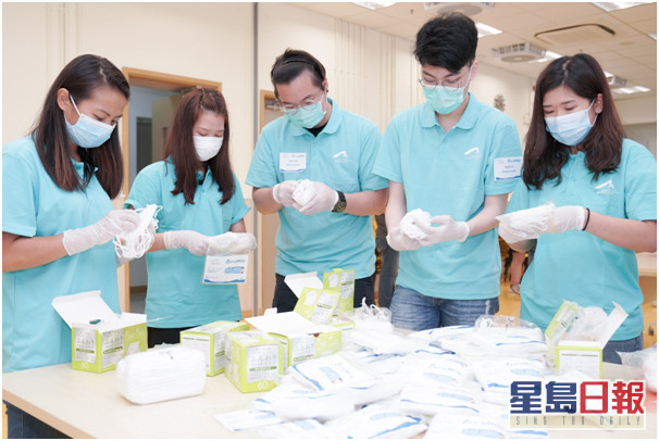 防疫大使准备派发物资,小心翼翼把口罩包好以便向东涌街坊分发。 机管局提供