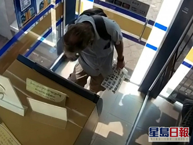 ATM機前的男子試圖從褲子口袋裡抽出一張鈔票,但在過程中,庫克向自己的手指塗上口水。(網圖)