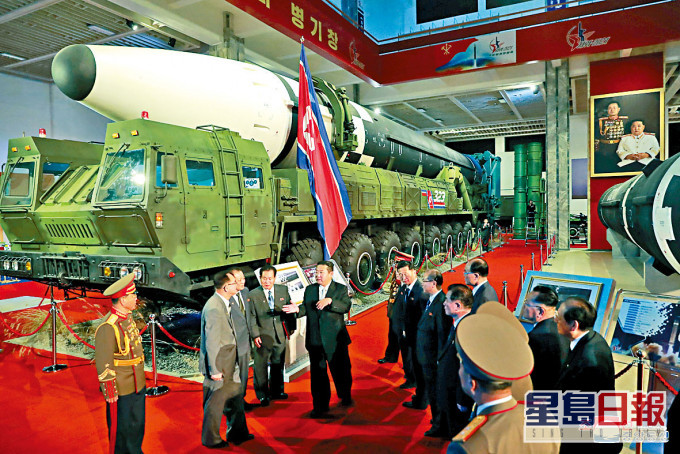金正恩於武器展場上與官員交談。