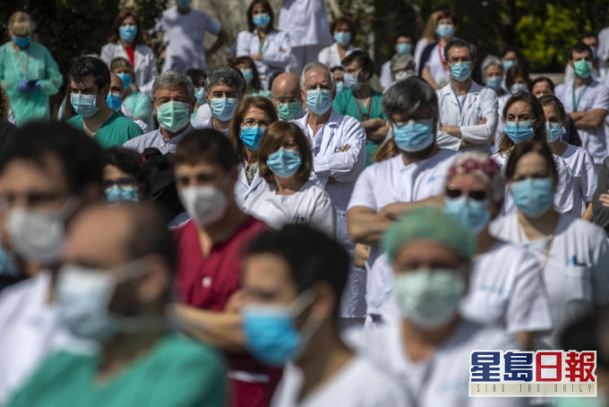 西班牙大批前線醫護為一名感染新冠肺炎殉職的外科主任默哀1分鐘。AP圖