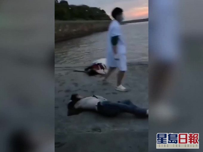 片段中,有兩人倒在沙灘上,渾身濕透。(網圖)