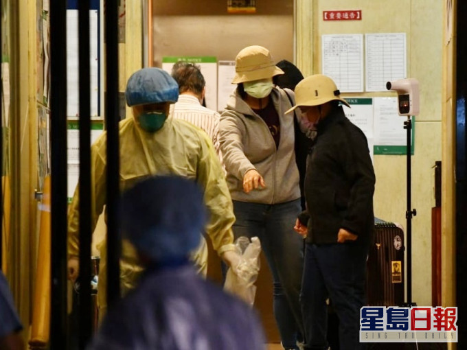 有3名文华阁居民在卫生署职员陪同下拖著行李箱离开。