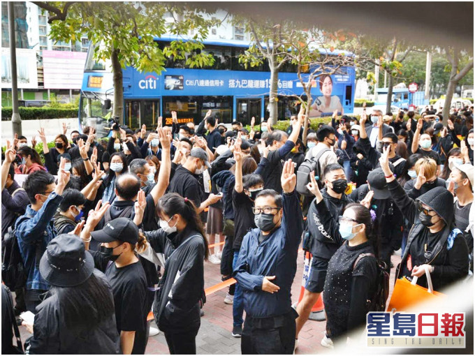 大批市民到法院外輪候公眾席籌號,有人高舉手勢。
