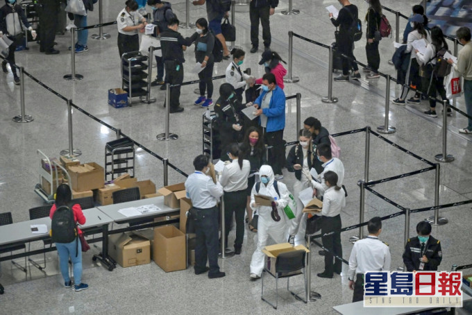 入境处及机场人员替抵港人士戴上追踪手带。资料图片。