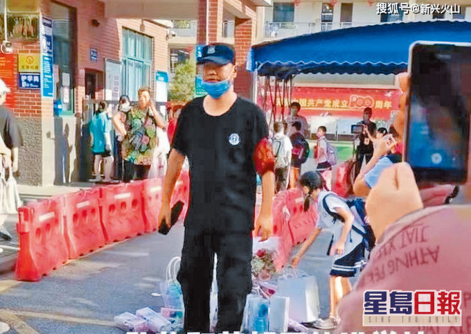 ■小學門外有保安要求學生放下鮮花和禮物才能入校。