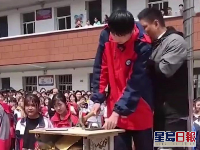 学生排队上台拿起小锤砸手机。网图